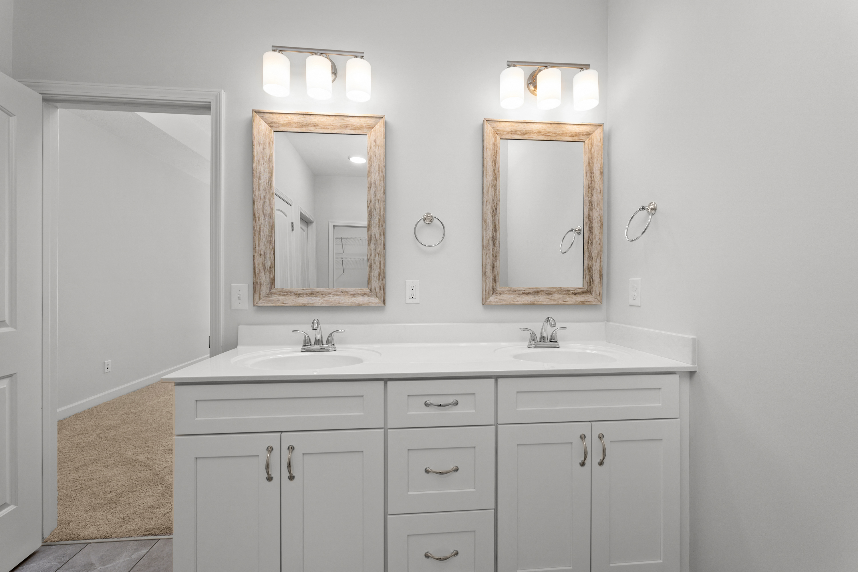 a white bathroom with two mirrors and two sinks