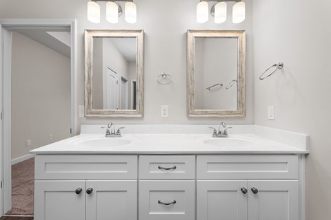 a white bathroom with two mirrors and two sinks