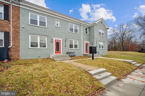 the front of a gray house with red doors