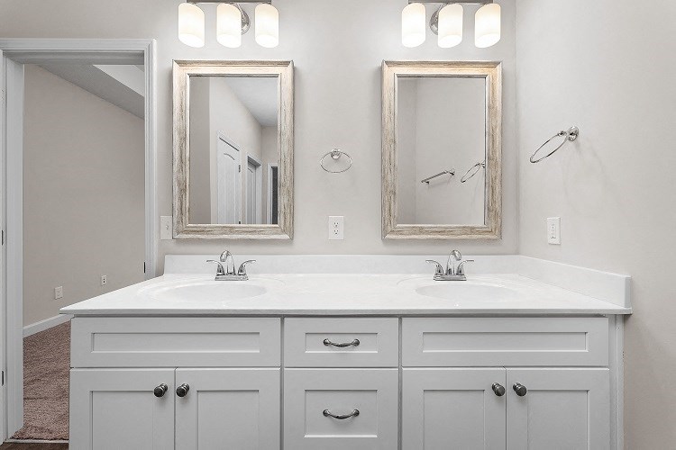 a white bathroom with two sinks and two mirrors