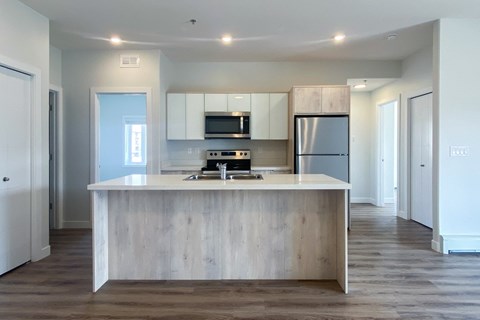 A modern kitchen with a white island and wooden cabinets.