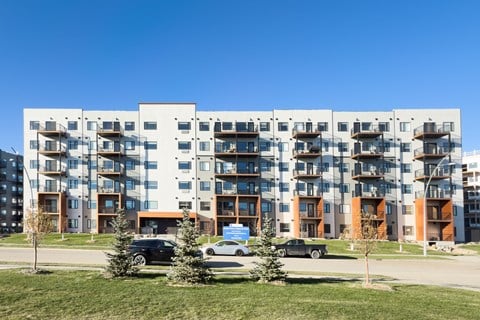A large apartment building with cars parked in front.