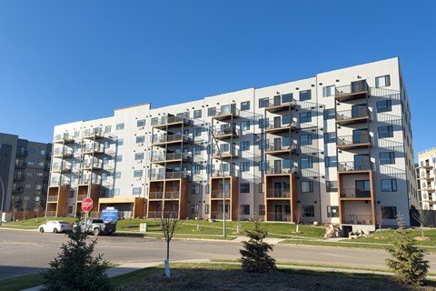 A large white building with balconies and a stop sign in front of it.
