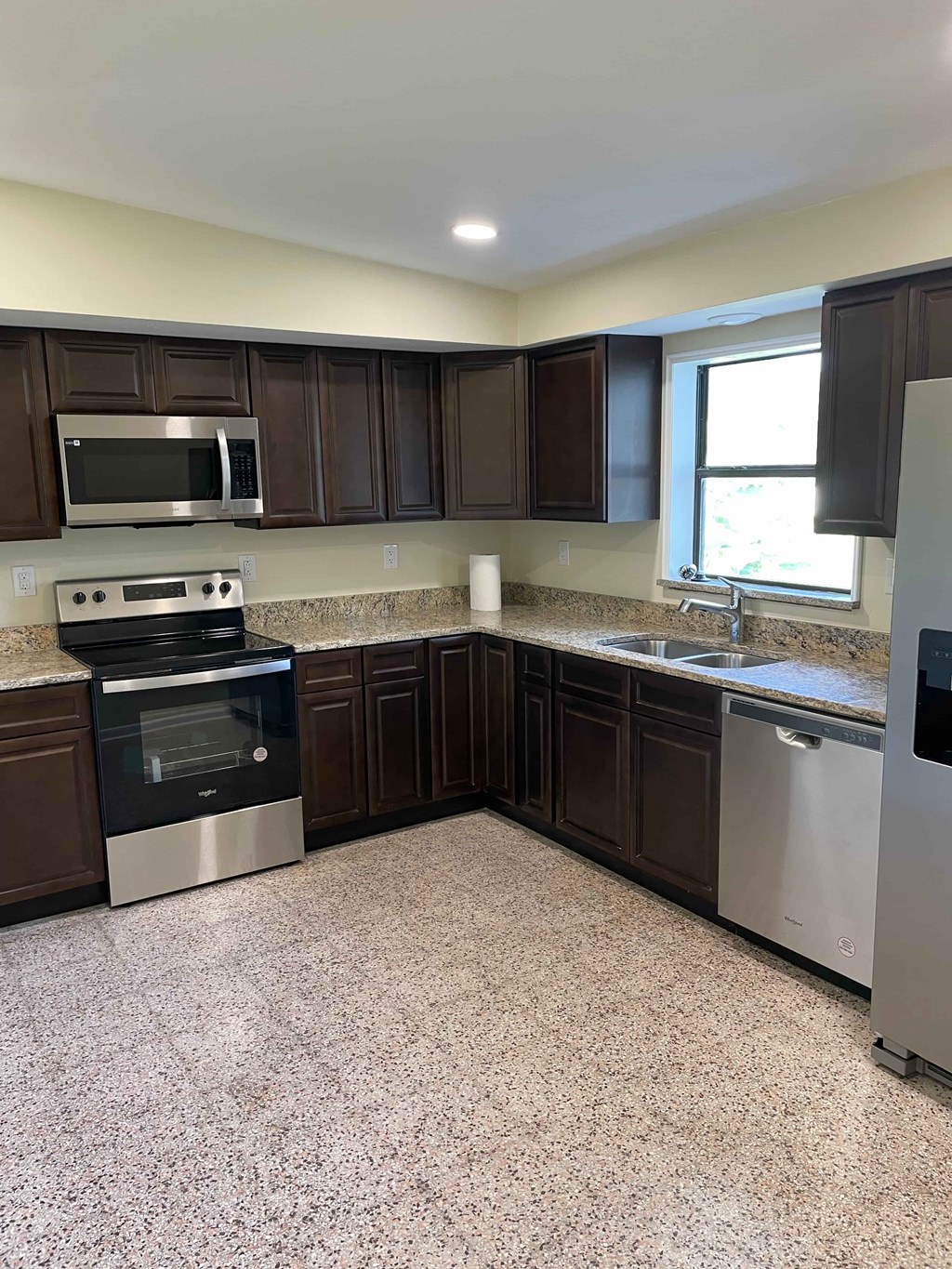 A kitchen with brown cabinets and a granite countertop.