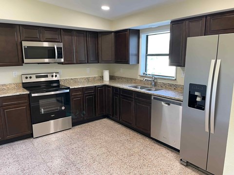 A kitchen with dark brown cabinets and stainless steel appliances.
