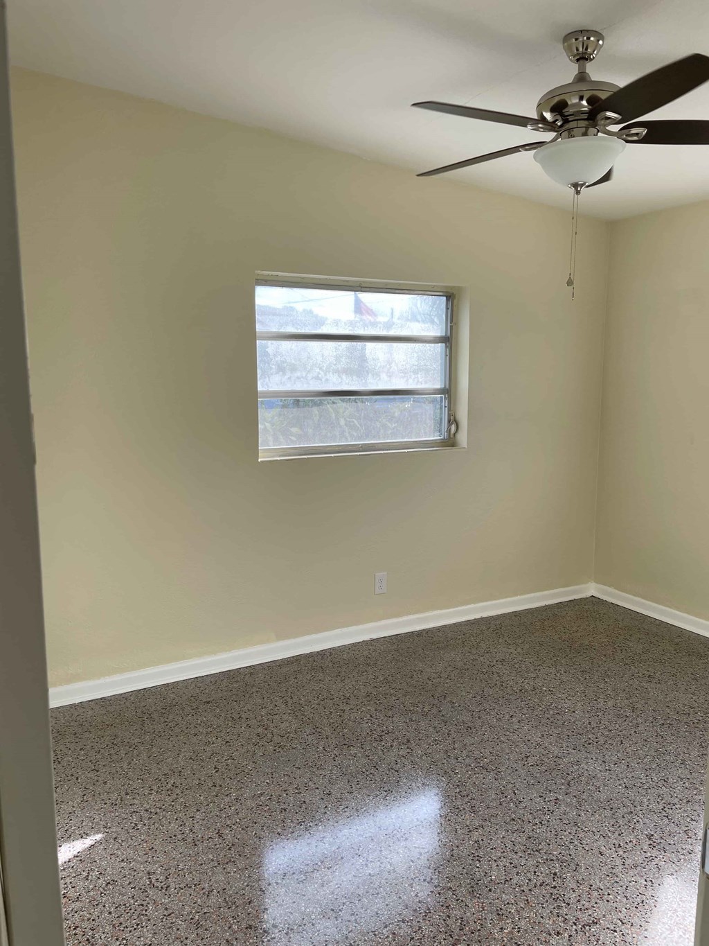 A room with a ceiling fan and a window.