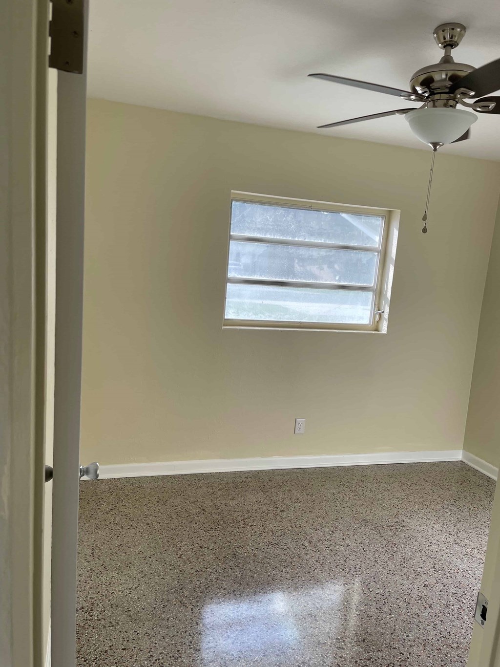 A room with a ceiling fan and a window.