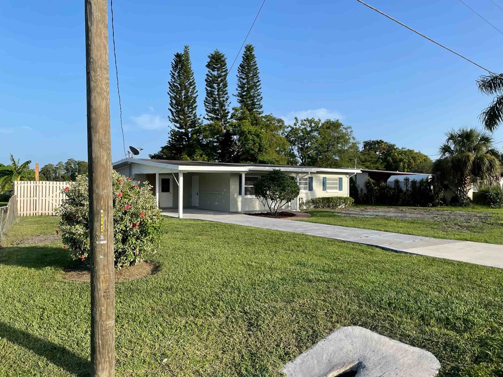 A house with a green lawn and a utility pole in the foreground.