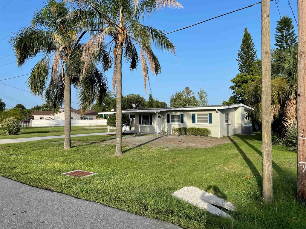 A house with a green lawn and a palm tree in front.