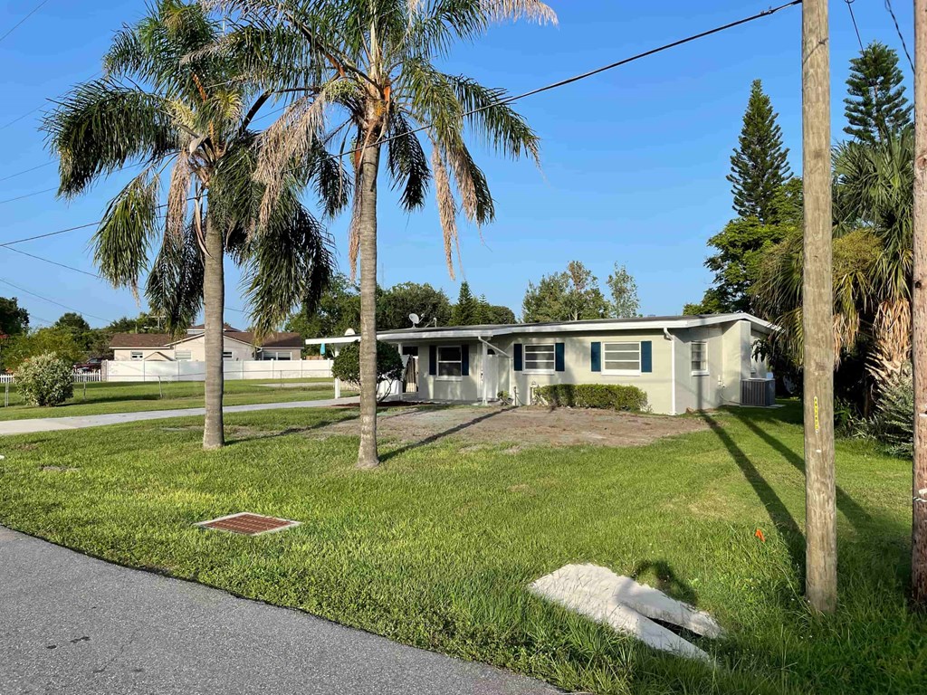A house with a white fence and a green lawn with a palm tree in front.