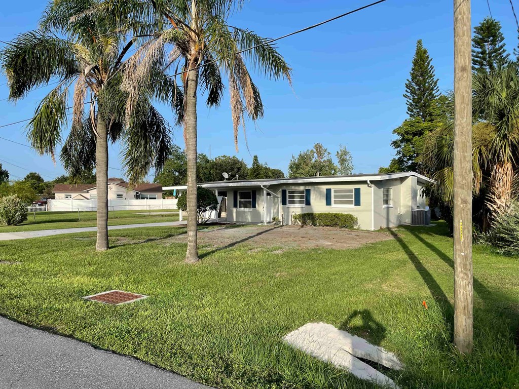 A house with a green lawn and palm trees in front.