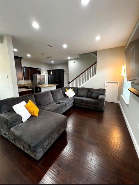 A living room with a grey couch and a wooden floor.