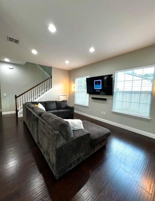 A living room with a grey couch and a television on the wall.
