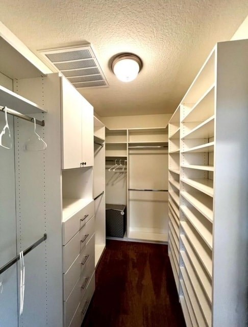 A long white hallway with a refrigerator on the left and a white door on the right.