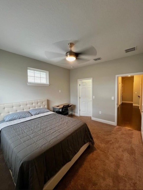 A bedroom with a bed, a ceiling fan, and a window.