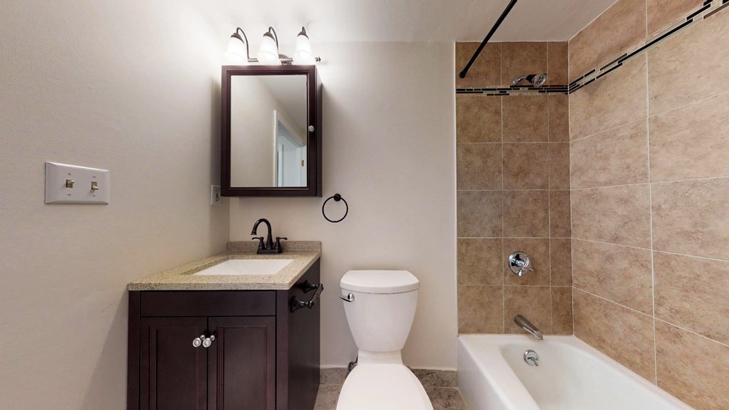 A bathroom with a toilet, sink, and mirror.