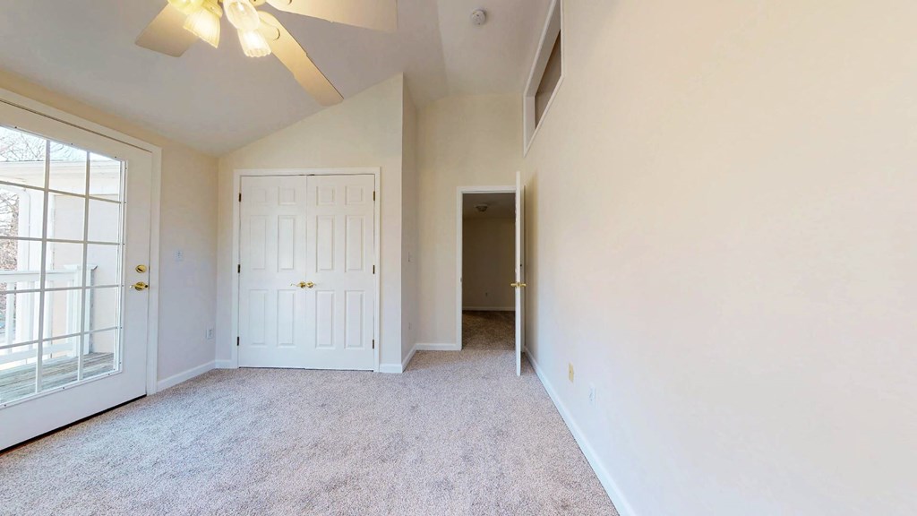 A room with a ceiling fan and carpeted floor.
