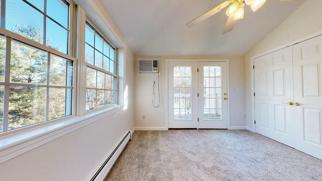 A room with a ceiling fan and a window overlooking trees.