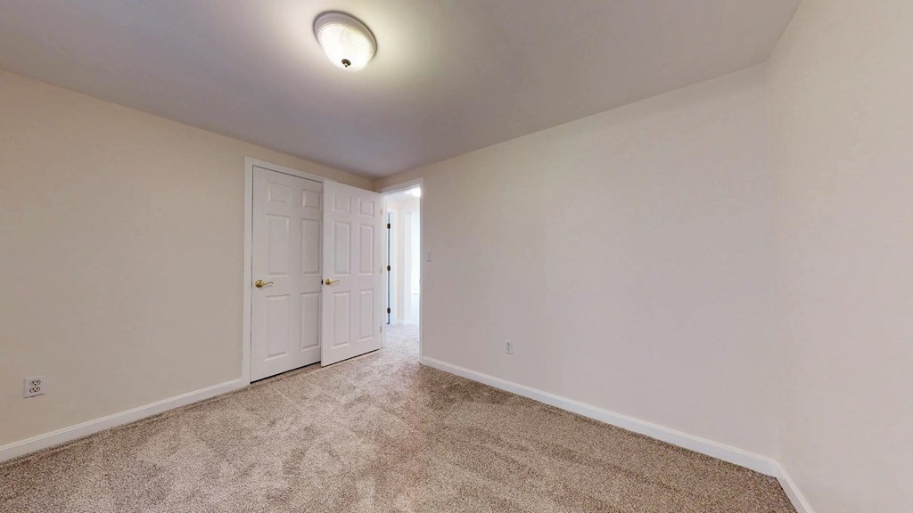 A room with a carpeted floor and a white door.