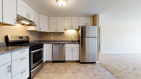 A kitchen with white cabinets and a black countertop.