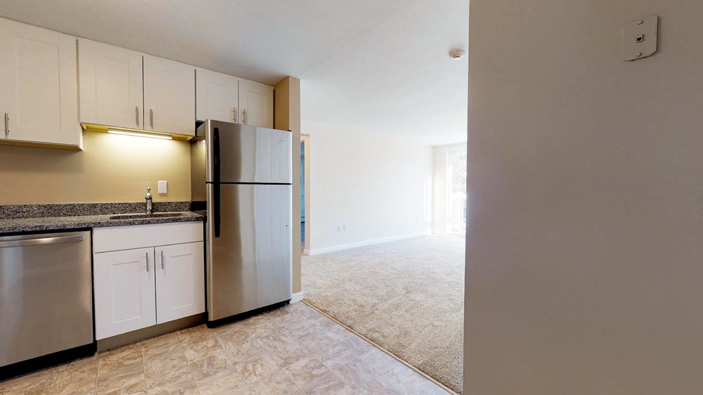 A kitchen with a refrigerator, dishwasher, and cabinets.