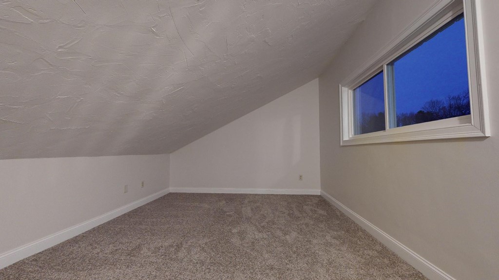A room with a carpeted floor and a window.