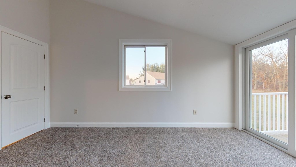 A room with a carpeted floor, a window, and a door.