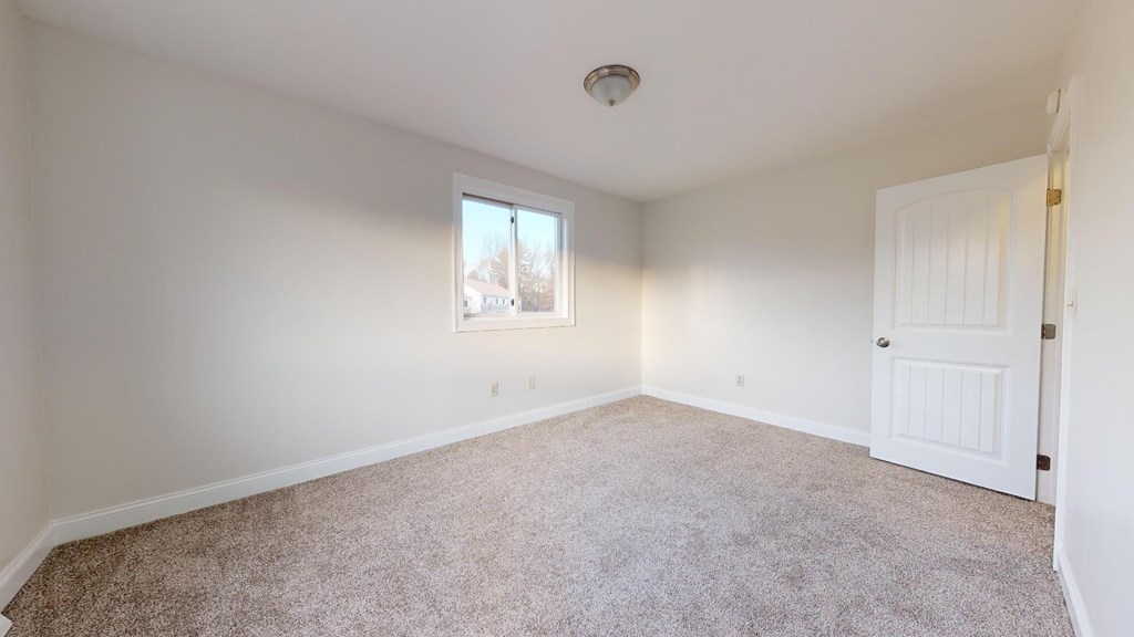 A room with a carpeted floor and a window.