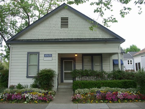 A small white house with a flower bed in front.