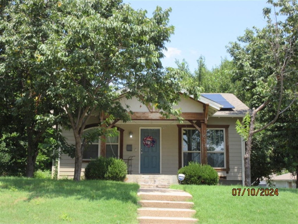 A house with a green lawn and trees in front of it.