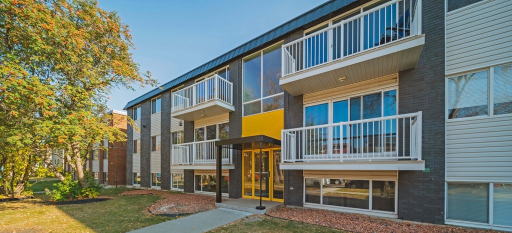 a building with balconies and a sidewalk in front of it