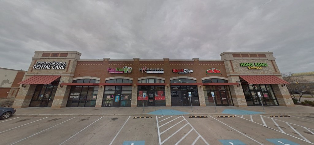 the front of a shopping center with a parking lot