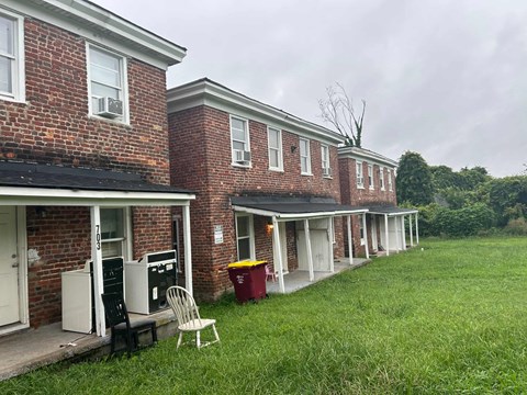 the front of a brick building with a lawn and a rocking chair