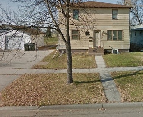 a house on the corner of a street with a tree