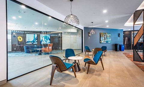 A modern living room with blue chairs and a glass wall.