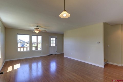 A spacious room with a ceiling fan and wooden flooring.