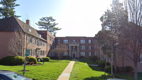 the front of a building with a lawn and trees