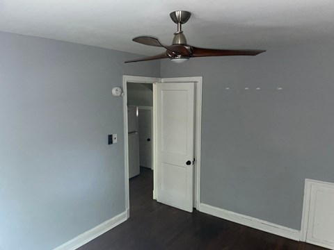 a bedroom with a ceiling fan and a door to a hallway