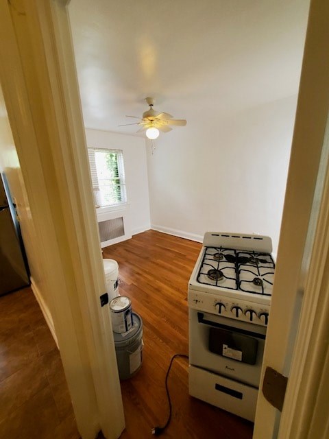 A white gas stove is in a room with a fan on the ceiling.