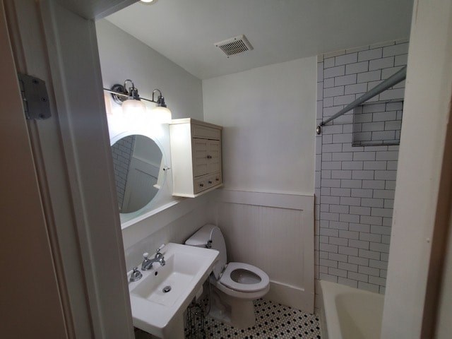 A bathroom with a toilet, sink, and mirror.