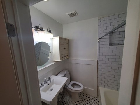 A bathroom with a toilet, sink, and mirror.