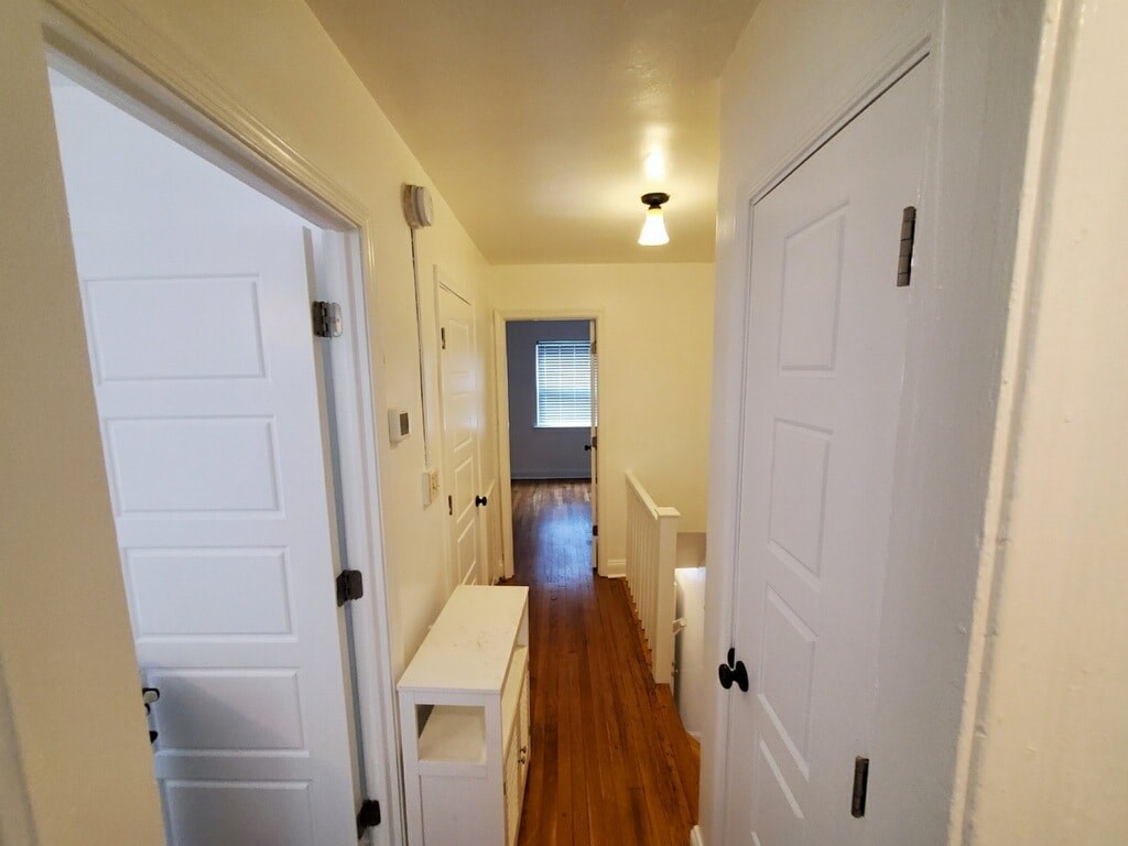 A long hallway with white doors and a bench.