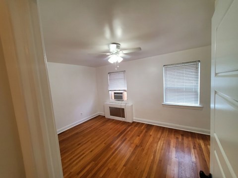 A room with wooden floors and a window with blinds.
