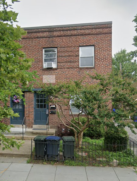 a brick building with three trash cans in front of it