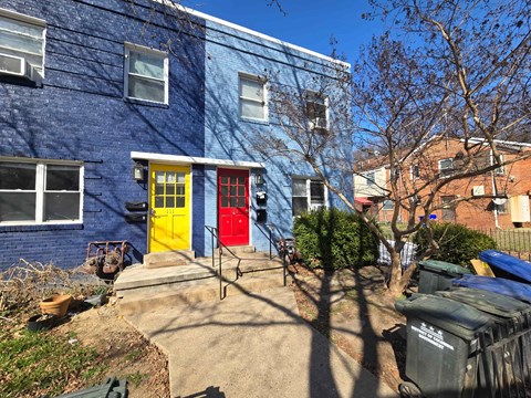 A blue building with a yellow door and red window shutters.