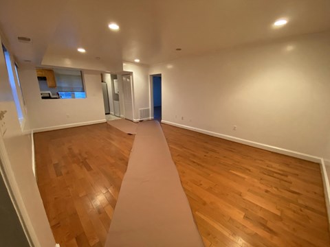 an empty living room with wood floors and a large rug