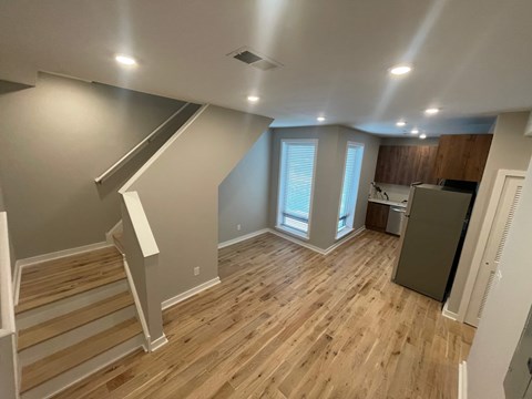 an empty living room with hard wood floors and a kitchen