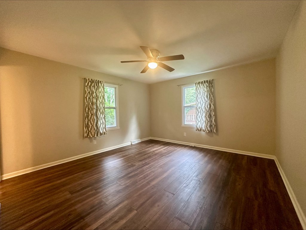 an empty living room with wood floors and a ceiling fan