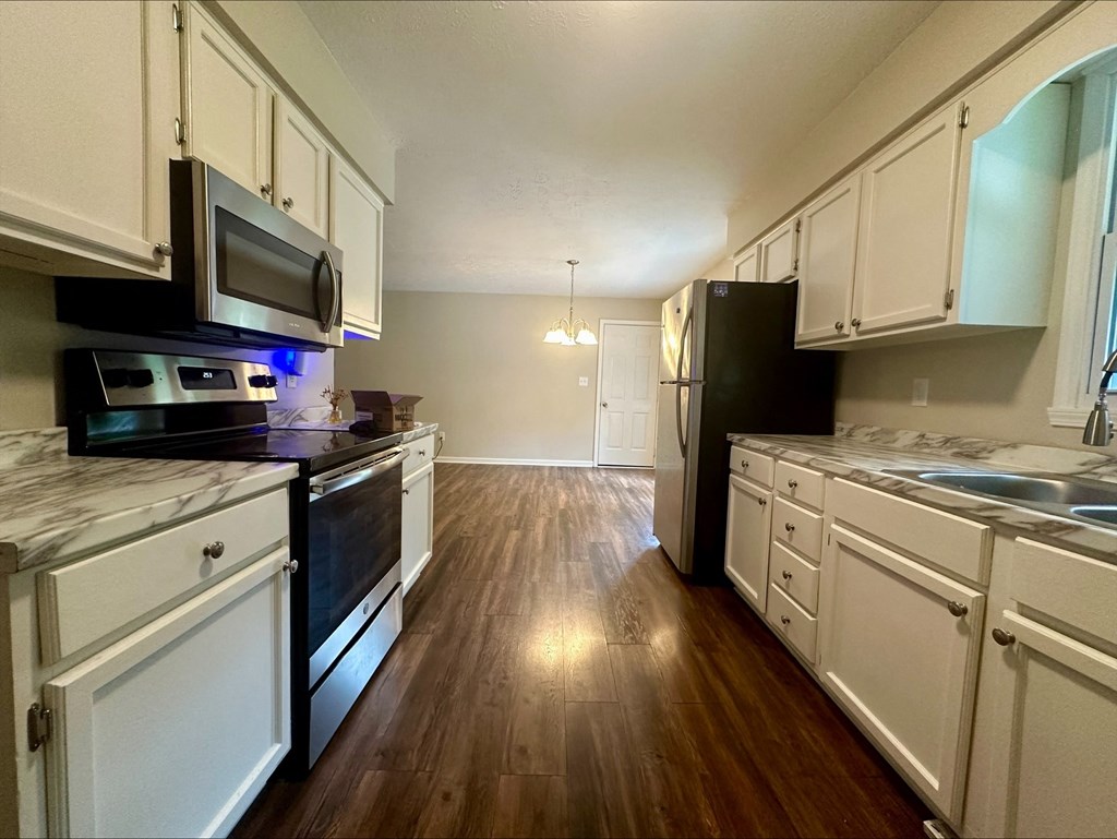 an empty kitchen with white cabinets and stainless steel appliances