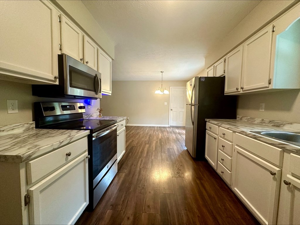 an empty kitchen with white cabinets and stainless steel appliances